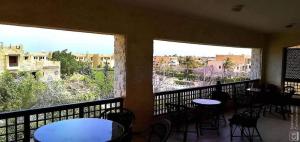 un balcone con tavoli e sedie e due grandi finestre di Four bed rooms chalet in marina 7 a El Alamein