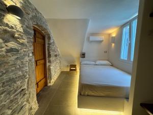 a bedroom with a bed and a stone wall at Servena's Damarionas Village in Náxos