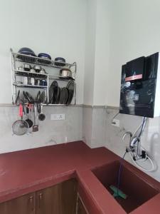 a kitchen with a sink and a tv on a wall at KAPOOR SAHAB HOMESTAY COUNTRYSIDE Its a home away from home in Saraia