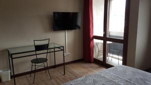 Schlafzimmer mit einem Schreibtisch, einem TV und einem Bett in der Unterkunft Hotel De La Gare in Aix-les-Bains