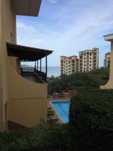 a view of a building with a swimming pool and some buildings at Sunset Heights 402 in Playa Flamingo