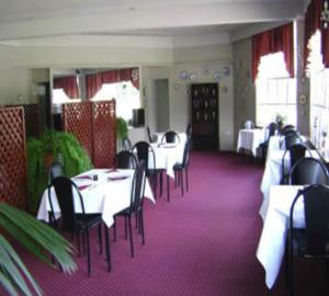 a dining room with white tables and black chairs at River Park Motor Inn in Casino