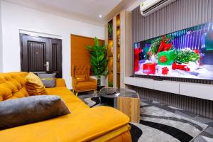 a living room with a yellow couch and a flat screen tv at Bawuah Royal Apartments in Kasi