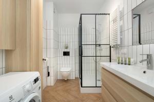 a bathroom with a shower and a washing machine at Rewal Cozy Apartment with Parking, Gym, Spa & Pool close to the Beach by Noclegi Renters in Rewal