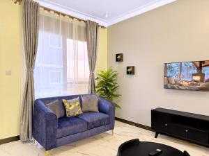 a living room with a blue couch in front of a window at Arana Royal Homes in Kampala