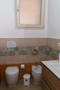 a bathroom with a toilet and a sink and a mirror at Boulevard Holiday in Avola +6 photos