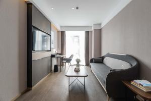 a living room with a couch and a tv at Atour Hotel Industrial Park Dongsha Lake in Suzhou