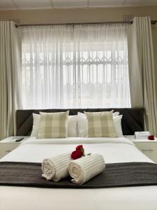 a large white bed with a rose on top of it at Kilimanjaro Lodge Bed & Breakfast in Johannesburg +60 photos