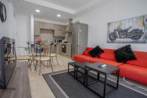 a living room with a red couch and a kitchen at 1-2BD Beach Apartments in Paphos