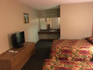 a hotel room with a bed and a flat screen tv at Knights Inn Merrillville in Merrillville