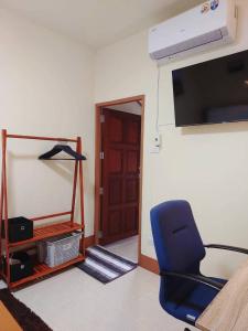 a room with a blue chair and a tv and a door at Stay&Stitch in Chiang Rai +2 photos