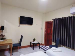 a room with a bed and a table and a tv on the wall at Stay&Stitch in Chiang Rai