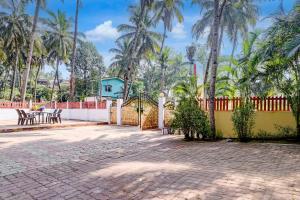 a driveway with a fence and palm trees at Hotel O Benaulim Beach Goa in Goa +41 photos