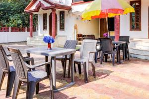 a group of tables and chairs and an umbrella at Hotel O Benaulim Beach Goa in Goa