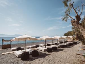 a row of umbrellas and lounge chairs on a beach at Sagredo Boutique Hotel & Spa in Ágios Fokás