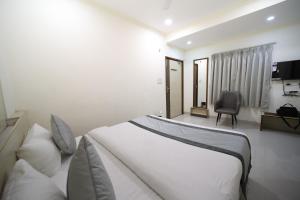 a bedroom with a large white bed and a chair at Hari Haran Prestige in Varanasi