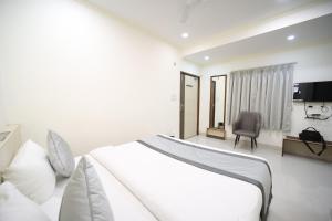 a white bedroom with a large bed and a chair at Hari Haran Prestige in Varanasi