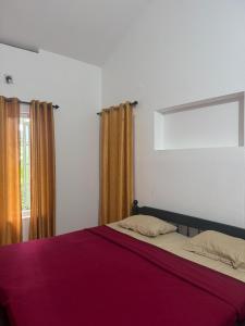 Un dormitorio con una cama con sábanas rojas y una ventana en Bamboo Heritage, en Vythiri