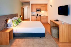 a bedroom with a large bed and a kitchen at NH Marina Portimao Resort in Portimão