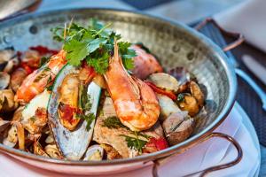 a pan filled with seafood and vegetables on a table at NH Marina Portimao Resort in Portimão