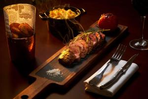 a steak on a plate on a table with a bottle of wine at NH Marina Portimao Resort in Portimão