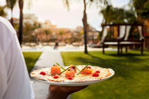 a person holding a plate with a pizza on it at NH Marina Portimao Resort in Portimão
