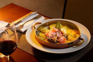 a bowl of food on a plate next to a glass of wine at NH Marina Portimao Resort in Portimão