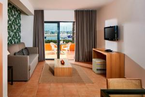 a living room with a couch and a tv at NH Marina Portimao Resort in Portimão