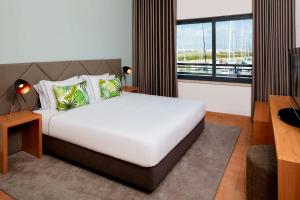 a bedroom with a large bed and a large window at NH Marina Portimao Resort in Portimão