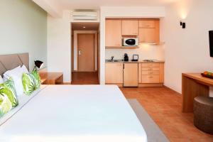 a bedroom with a large bed and a kitchen at NH Marina Portimao Resort in Portimão