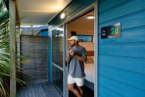 a man standing outside of a building taking a picture at Tasman Holiday Parks - Coromandel in Coromandel Town
