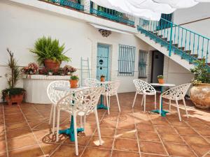 a patio with white chairs and tables and stairs at El Nogal Home in Málaga