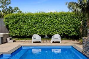 due sedie e un tavolo accanto a una piscina di Amaroo - poolside studio near Pukekura Park a New Plymouth