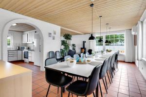 a dining room and kitchen with a long table and chairs at Large Pool House For 24 People, With Almost Everything In Activities, 300 Meters From The Fjord in Vinderup