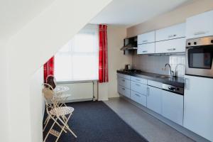 a small kitchen with white cabinets and a window at Appartement Spoorklokken in Bergen aan Zee