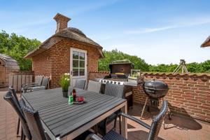 a patio with a wooden table and a grill at Large 18-Person Pool House With Outdoor Hot Tub, Outdoor Sauna And Enclosed Terrace in Ulfborg
