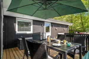 a table with a green umbrella on a deck at Lovely Renovated Holiday Home With A Wilderness Bath And Fenced Grounds in Vesløs