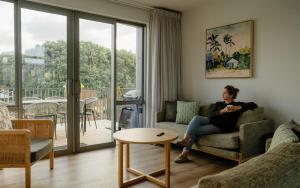 a woman sitting on a couch in a living room at Tasman Holiday Parks - Papamoa Beach in Papamoa