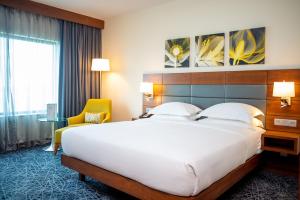a hotel room with a large bed and a yellow chair at Hilton Garden Inn Nairobi Airport in Nairobi