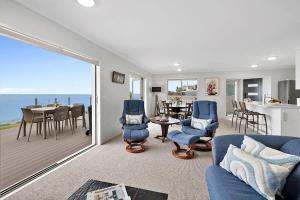 a living room with a blue couch and a dining room at Beachfront Breeze - sea views for days in New Plymouth +17 photos