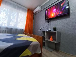 a bedroom with a bed and a flat screen tv on the wall at Комфортная квартира Сабитовой 23а, район ЖД вокзал in Balqash +32 photos