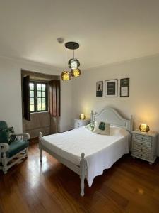 a bedroom with a large white bed and a chair at Quinta Do Sobreiro in Vila Verde