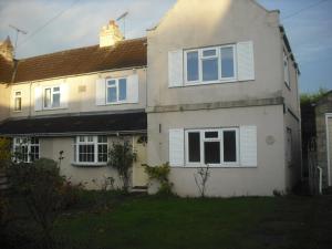 ein weißes Haus mit weißen Fenstern und einem Garten in der Unterkunft Lilac Farm Cottage in Collingham