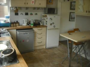 eine Küche mit einem weißen Kühlschrank und einem Tisch in der Unterkunft Lilac Farm Cottage in Collingham