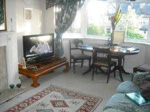 ein Wohnzimmer mit einem TV, einem Tisch und einem Sofa in der Unterkunft Lilac Farm Cottage in Collingham