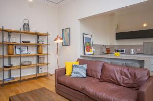a living room with a brown couch and a kitchen at Spacious Period Property in Glasgow in Glasgow