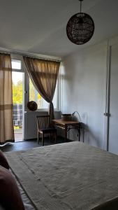 バトゥミにあるGuesthouse in Green Capeのベッドとテーブルと窓のある寝室