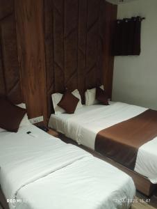 two beds sitting next to each other in a room at Hotel Pera Villa in Gandhinagar