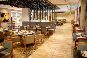 a dining room with tables and chairs in a restaurant at Hilton Garden Inn Nairobi Airport in Nairobi