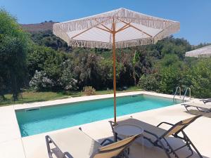 a table and chairs under an umbrella next to a swimming pool at Villa Evridiki in Georgioupolis